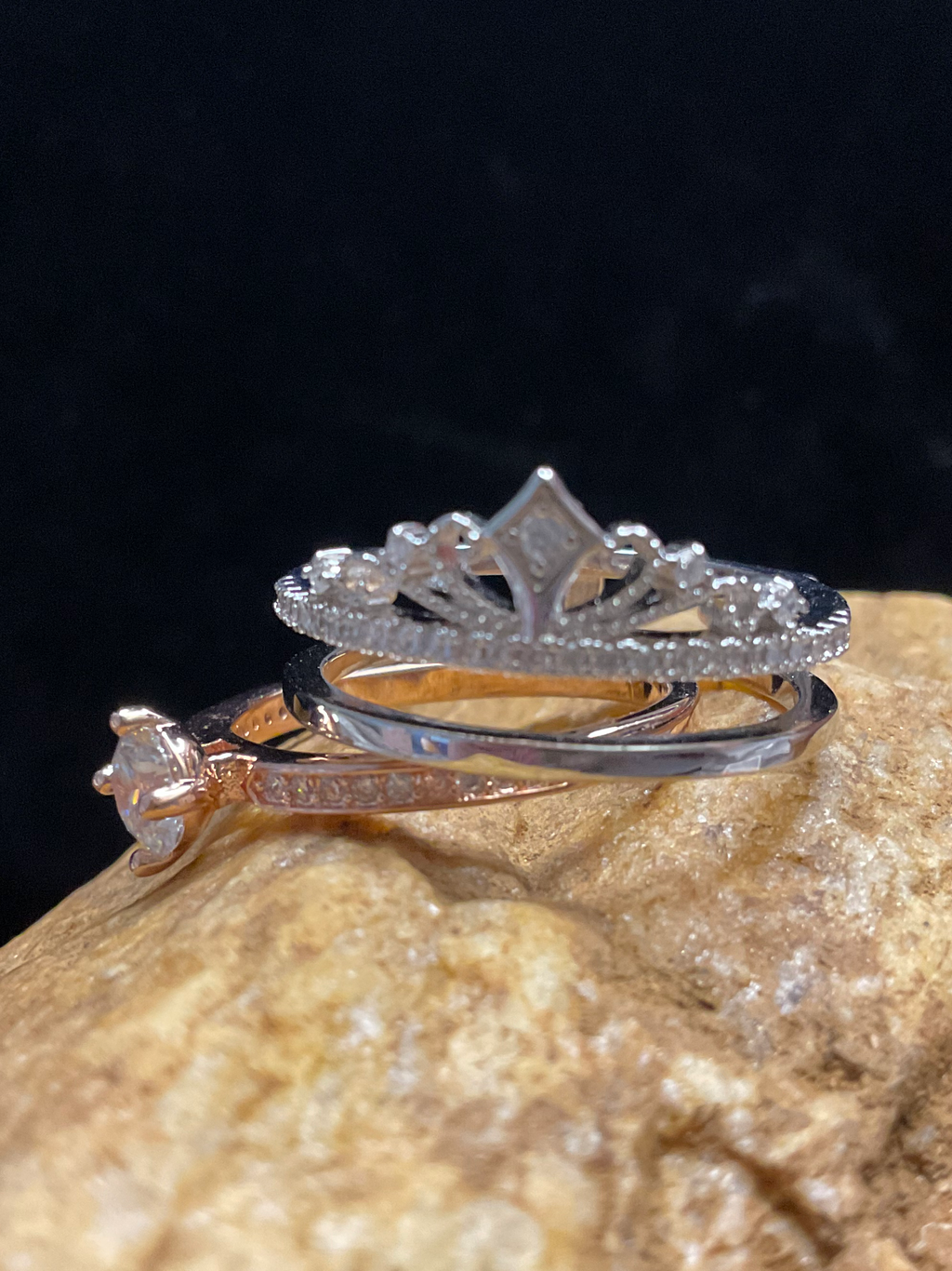 Two silver rings on a textured stone surface with a dark background