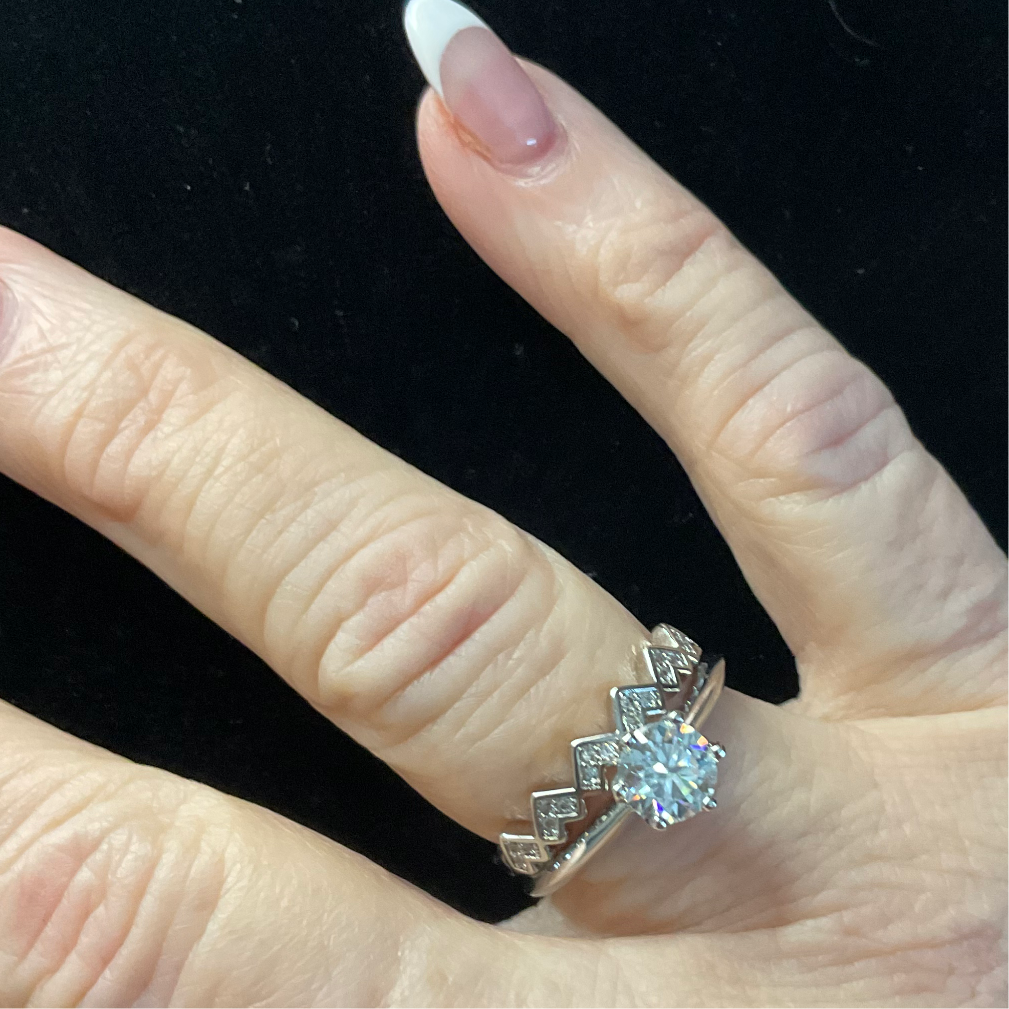 Hand wearing a silver ring with a blue gemstone on a black background