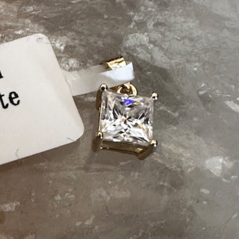 Diamond pendant on a gray stone surface with a label