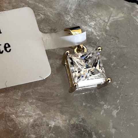 Gold earring with a clear gemstone on a gray surface