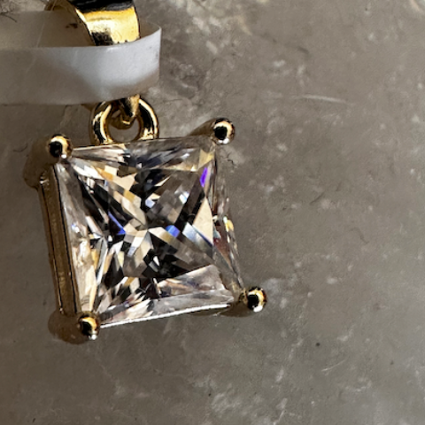 Gold pendant with a large clear gemstone on a gray surface