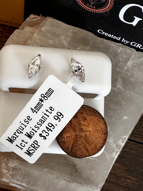 Pair of marquise cut earrings on a display stand with a price tag and coin for scale.