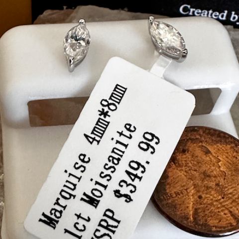 Pair of marquise-shaped gemstone earrings on a white stand with a price tag.