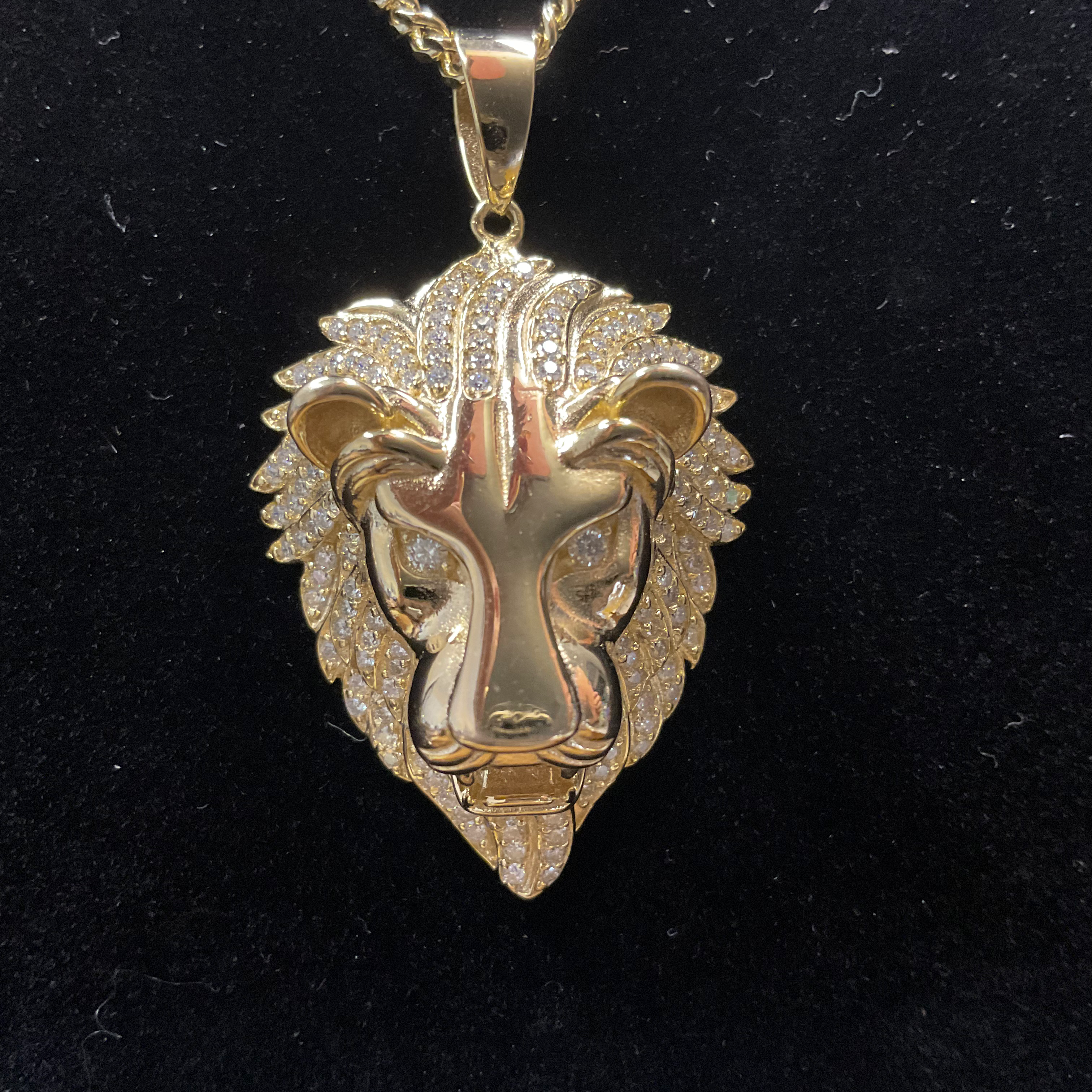 Gold lion head pendant on a black background