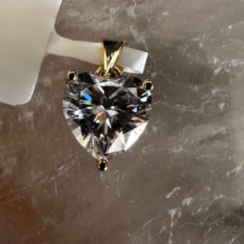 Diamond pendant on a gray surface with a label in the background