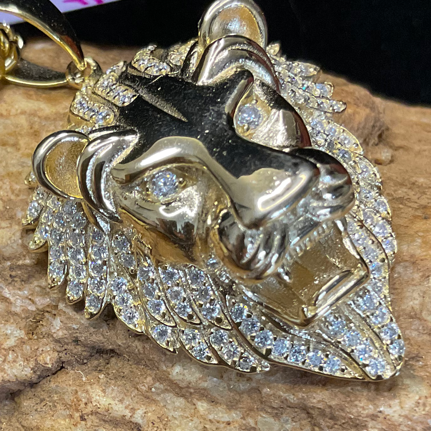 Gold chain with a lion pendant on a stone surface