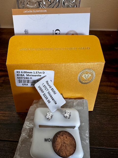 Diamond earrings with a gold box and certificate on a wooden surface