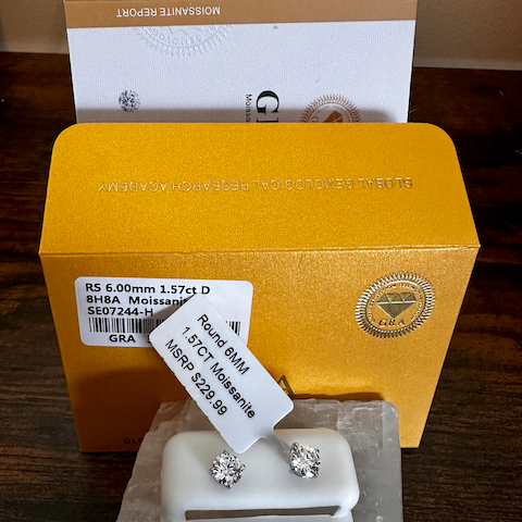 Diamond earrings on a display stand with a yellow box in the background