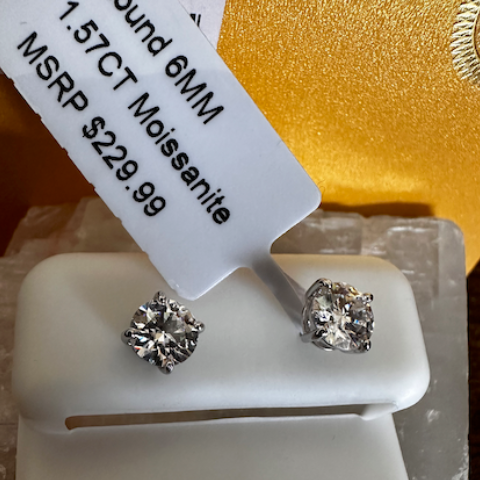 Pair of moissanite earrings on a display stand with a price tag.