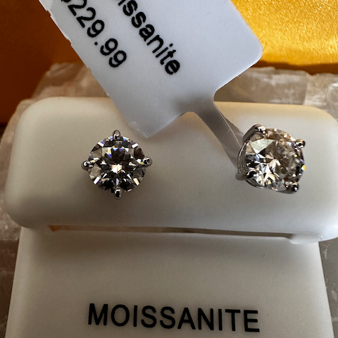Pair of moissanite stud earrings on a display card with price tag.
