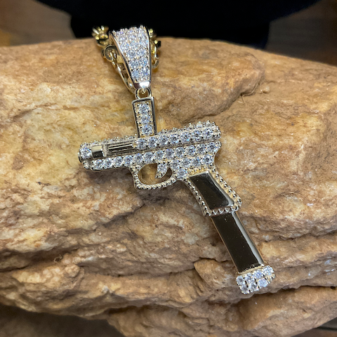 Pendant shaped like a gun with diamonds on a stone surface
