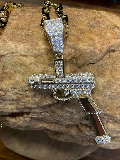 Diamond-studded gun-shaped pendant on a rock