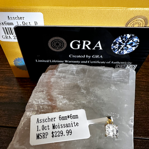 Moissanite pendant with 'GRA' certification on a stone surface