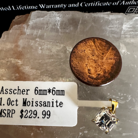 Asscher-cut moissanite with a penny for scale on a stone surface