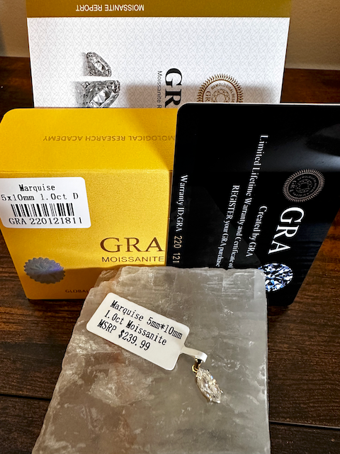Diamond jewelry with GRA Moissanite packaging on a wooden surface