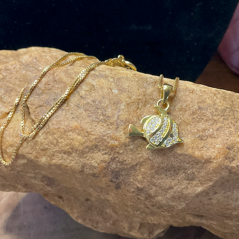 Gold necklace with a heart-shaped pendant on a stone surface