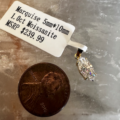 Marquise-shaped moissanite pendant on a stone surface with a coin for scale.