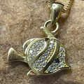 Gold fish-shaped pendant with embedded stones on a stone surface