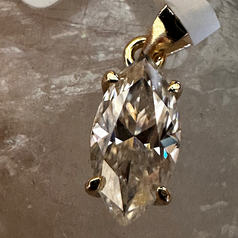 Gold earring with clear gemstone on a gray background