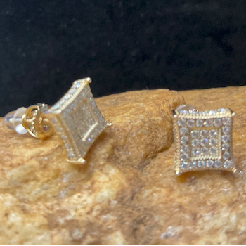 Gold square-shaped earrings on a dark background