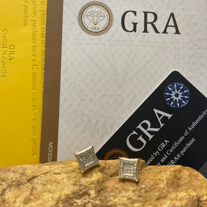 Gold square stud earrings on a rock with GRA certification card in the background
