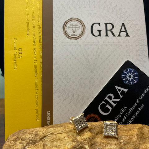 Gold square earrings on a rock with GRA branding in the background