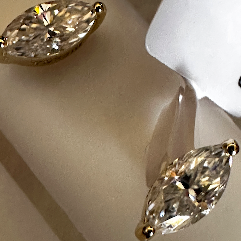 Close-up of marquise-shaped diamond earrings on a white stand.