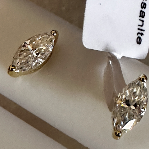 Pair of marquise-shaped diamond earrings on a white surface with 'Boucheron' branding.