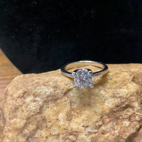 Silver ring with a diamond on a textured stone surface