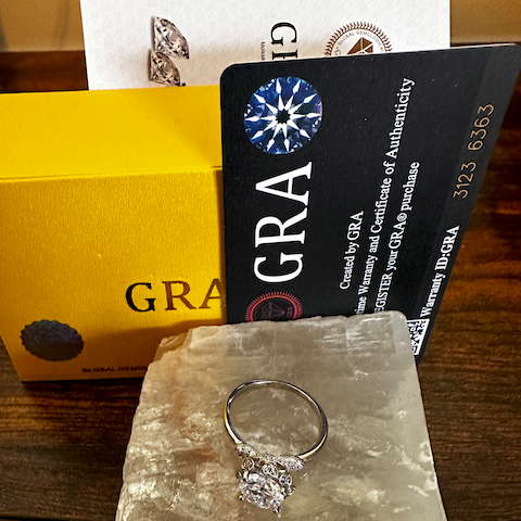 Diamond ring on a stone with GRA certification card and box in the background