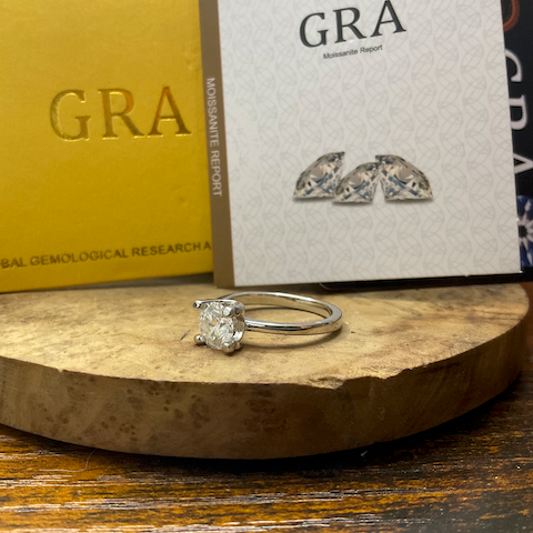 Diamond ring and earrings on a wooden stand with GRA branding in the background.