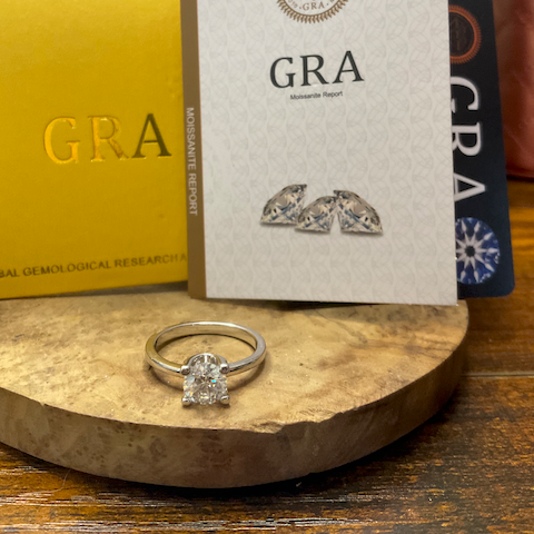 Diamond ring on a wooden stand with GRA brochures in the background