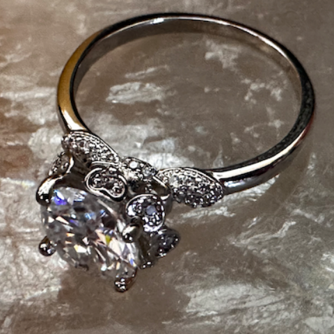 Silver ring with a large gemstone on a textured surface