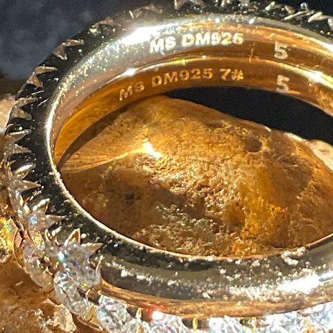 Close-up of a gold ring with engraved text on a dark background