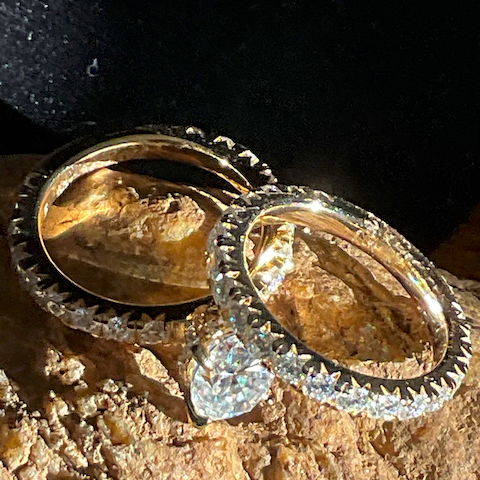Two gold rings with diamond accents on a textured surface