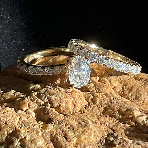 Two gold rings with diamond accents on a textured surface