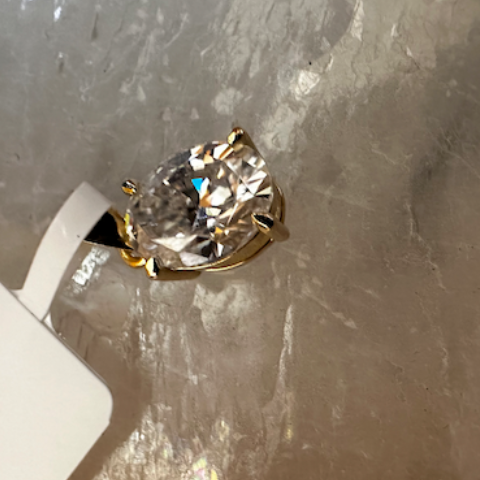 Gold ring with a clear gemstone on a textured surface