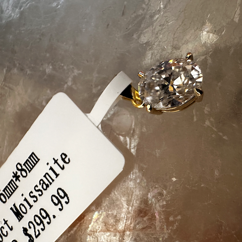 Gold ring with a large gemstone on a gray surface with a price tag.