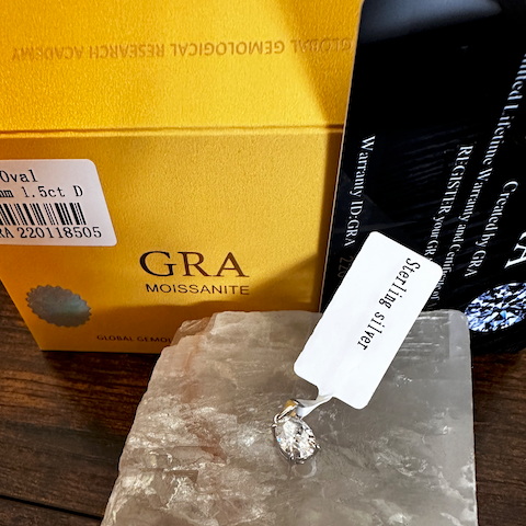 Diamond on a stone with 'GRA Moissanite' packaging in the background