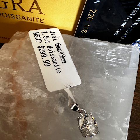 Diamond pendant on a rock with a price tag and brand name visible