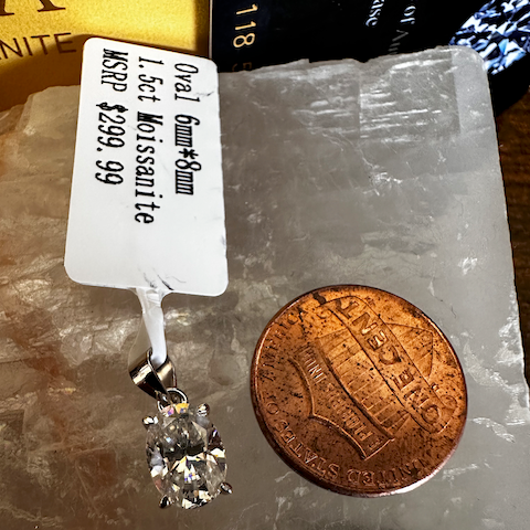 Diamond earring next to a penny on a clear stone surface