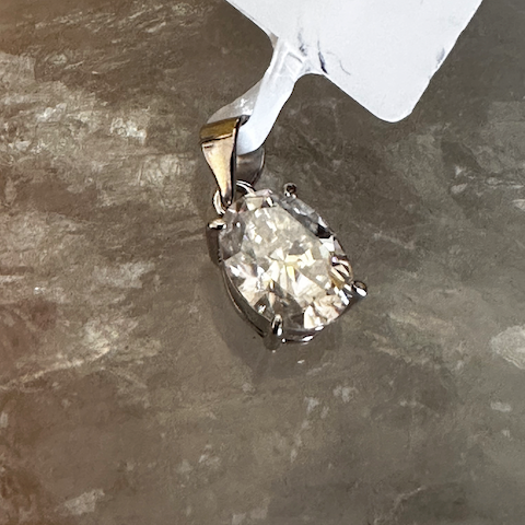 Diamond pendant on a gray surface with a price tag attached