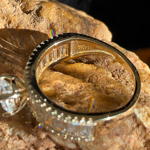 Gold ring with diamond accents on a rock background