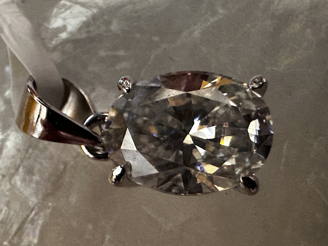 Close-up of a diamond earring on a textured gray background