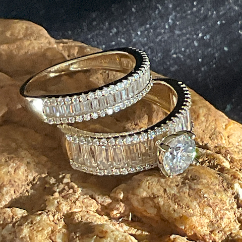 Two diamond rings stacked on a textured surface with a dark background