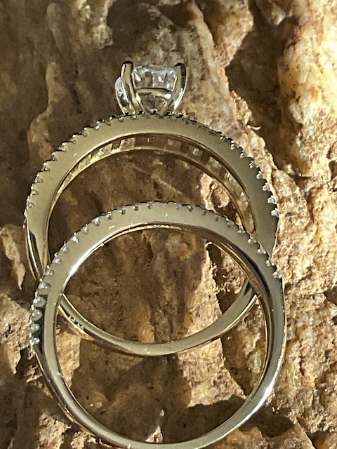 Two gold rings with diamond accents on a textured stone surface