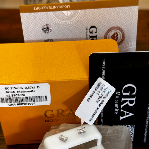 Diamond earrings on a stand with a Gravis box and documentation in the background.