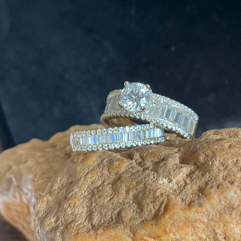 Two diamond rings on a textured stone surface with a dark background