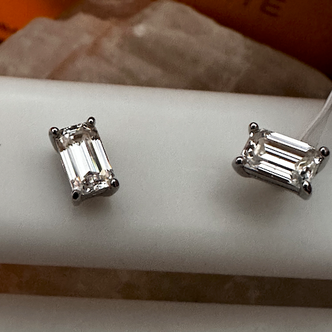 Pair of silver emerald-cut gemstone earrings on a white surface.