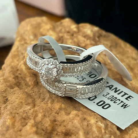Silver ring with gemstones on a stone surface with a price tag.